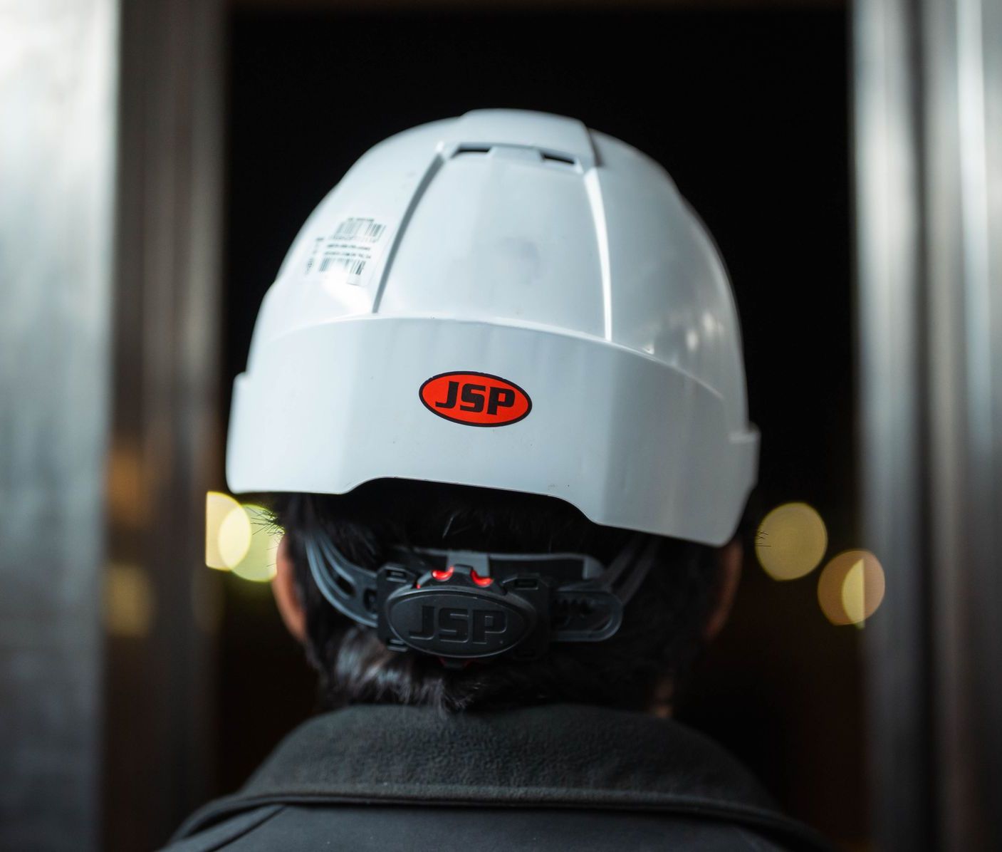 Capacete de segurança visto por trás, em ambiente industrial